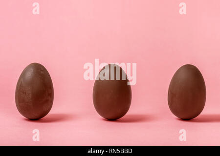 funny creative concept of chocolate Easter eggs on pink background, copy space Stock Photo