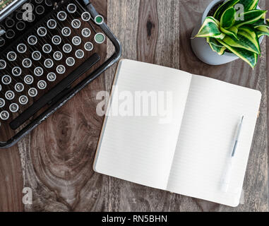 vintage typewriter and open diary or note pad on rustic wooden table Stock Photo