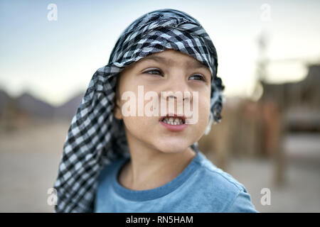 Small boy in checkered keffiyeh grimacing outdoors Stock Photo