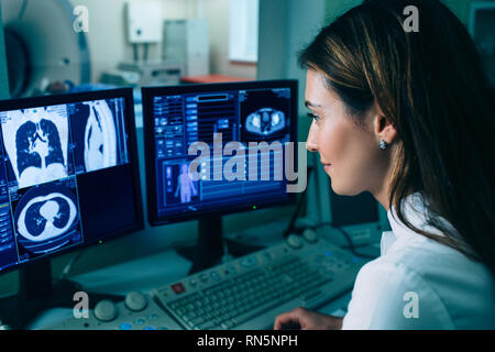 Radiologist reading a CT scan. Female doctor running CT scan from control room at hospital Stock Photo