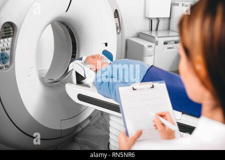 doctor write into medical chart after CT Scan Stock Photo