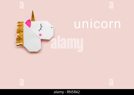 Origami bookmark in the shape of a Unicorn on a pink background. Top view. Stock Photo