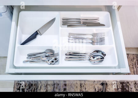 cutlery spoons forks knives and tea spoon on the shelf in the kitchen cupboard Stock Photo