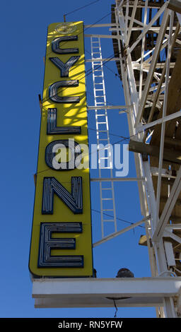 New York, USA. 16th February, 2019. Sun splashes onto the yellow, white, and blue Cyclone sign through the historic slats of this Surf Avenue wooden roller coaster at Luna Park at Coney Island in Brooklyn, on a blue-sky winter day in February. Originally built in 1927, this thrill ride was saved from demolition and later placed on the New York State Register of Historic Places in 1991. Recognized as an ACE Roller Coaster Landmark by the American Coaster Enthusiasts, the Cyclone has served as a backdrop for weddings, movies, and world-record riding marathons. Kay Howell/Alamy Live News Stock Photo