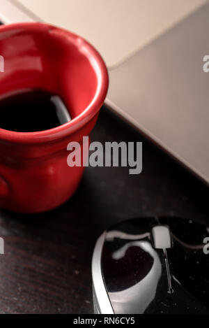 still life with blocknote, labtop, pen and a red cup of coffee over a black office desk. symbol of job Stock Photo