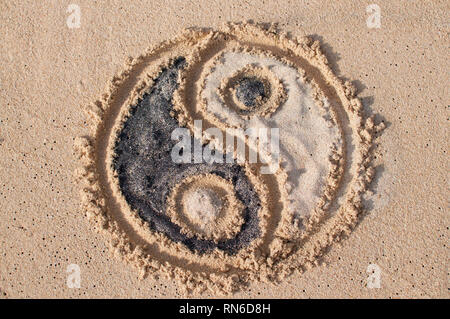 Yin-yang symbol is drawn and filled with black and white sand at Melasti beach in Bali, Indonesia Stock Photo