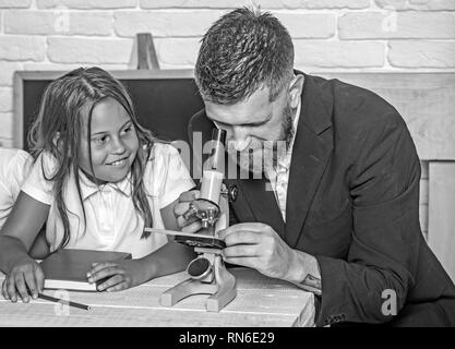 Biology lesson and study at laboratory with microscope. Back to school and home schooling. School time of sisters and father. Education in knowledge Stock Photo
