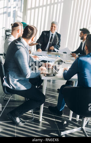 Indian business adviser analyzing company financial report shows documents with charts to Senior grey-haired investor discussing balance sheet data du Stock Photo
