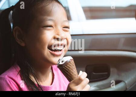 Asian child girl eating ice cream in car with smile and happy
