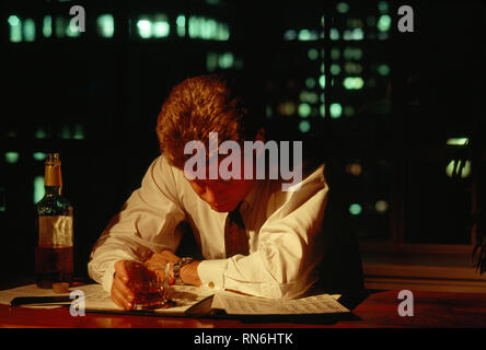 Businessman working late and drinking alcohol in his office, USA Stock Photo