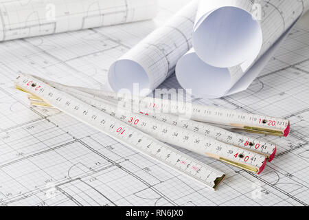 Rolls of architectural blueprint house building plans with folding rule on blueprint background on table Stock Photo