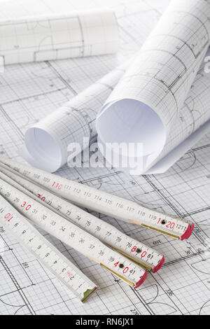 Rolls of architectural blueprint house building plans with folding rule on blueprint background on table Stock Photo