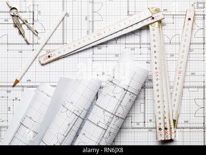 Rolls of architectural blueprint house building plans on blueprint background with folding rule, pencil and compasses on table flatlay top view from a Stock Photo