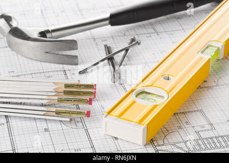 Construction tools  with hammer, nails, folding rule and level on architectural blueprint plan background Stock Photo