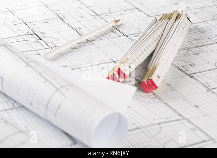 Rolls of architectural blueprint house building plans on blueprint background on table with pencil and folding rule Stock Photo