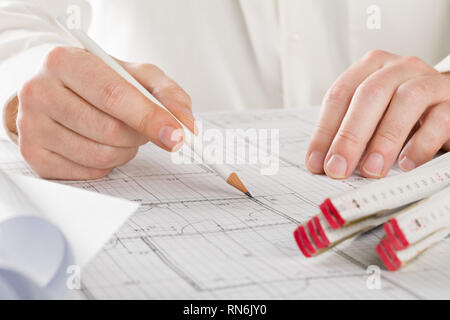 Architect pointing on architectural blueprint house building plan with pencil and folding rule Stock Photo