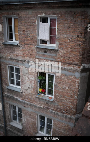 brick tenement house with washing and flowers in the windows Stock Photo