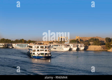 Nile cruise boat on river with ruins of Kom Ombo on riverbank Stock Photo