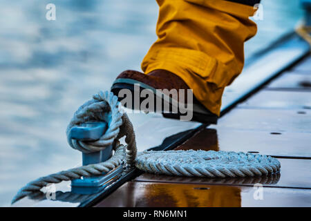 Coiled mooring line tied around cleat on a pontoon at rainy evening. Stock Photo