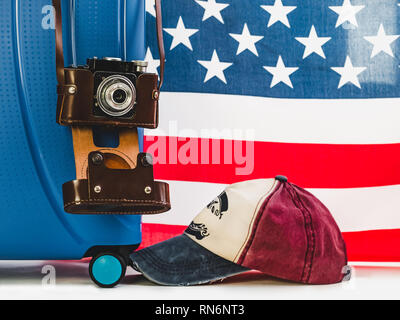 Stylish, blue suitcase, USA flag, vintage camera in a leather case on a white background, isolated. Close-up. Preparing for the summer trip Stock Photo