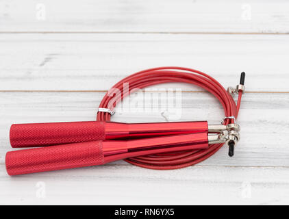 Modern red jump rope on white wooden background,flat lay Stock Photo