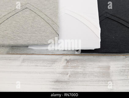 New black, white and grey v neck shirt on white wooden background Stock Photo