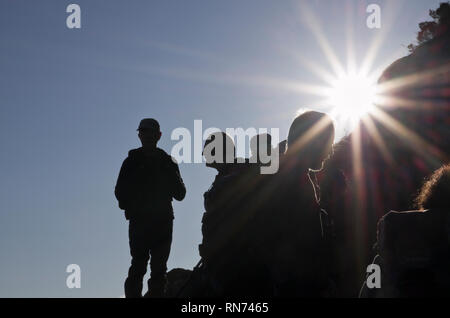 Hikers in silhouette against the sun on Mount Tryfan mountain in Snowdonia. Ogwen, North Wales, UK, Britain Stock Photo