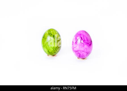 Close up of two painted easter eggs (green and purple) standing on white background Stock Photo