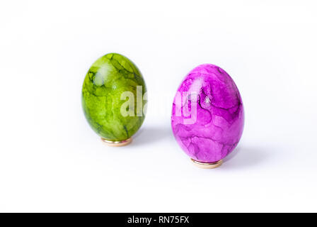 Close up of two painted easter eggs (green and purple) standing on white background Stock Photo
