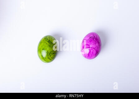 Flat lay of two colorful painted easter eggs laying on white background Stock Photo