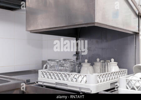 Clean utensils in the dishwasher in restaurant. Wine glasses, beer mugs, ceramic teapots. Concept of preparation for the opening, banquet, catering, b Stock Photo