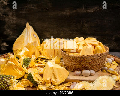 Peeled jackfruit in weaving basket with seed and shell on threshing basket agianst black cement wall background. Stock Photo