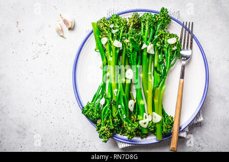 Boiled broccolini with garlic on a white plate. Plant based food concept. Stock Photo