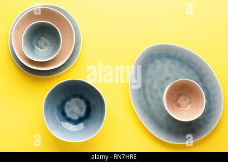 Beautiful blue, grey, beige dinnerware, plates bowls on yellow background table, top view, copy space, selective focus Stock Photo