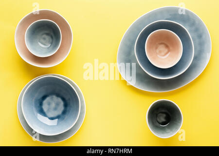 Beautiful blue, grey, beige dinnerware, plates bowls on yellow background table, top view, copy space, selective focus Stock Photo