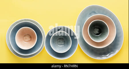 Beautiful blue, grey, beige dinnerware, plates bowls on yellow background table, top view, selective focus Stock Photo