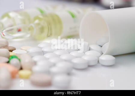 Scattered tablets, pills, ampules on white mirror background. Health care concept. Scattered supplements from plastic bottle. Stock Photo