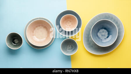 Beautiful blue, grey, beige dinnerware, plates bowls on blue yellow background table, top view, selective focus Stock Photo