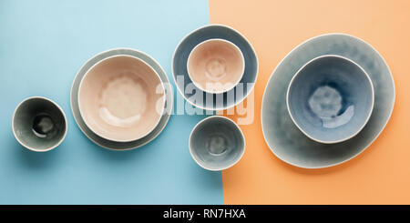 Beautiful blue, grey, beige dinnerware, plates bowls on blue pastel orange background table, top view, selective focus Stock Photo