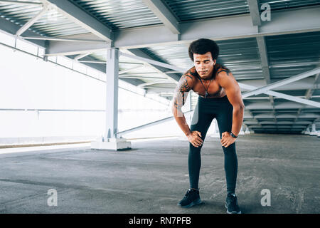 Muscular runner with eyes closed taking deep breath during intense training Stock Photo