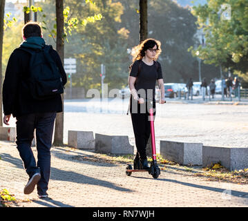 Strasbourg, Alsace, France, young woman riding her dockless electric scooter on pavement, Stock Photo