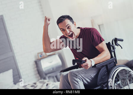 Favourite pastime. Joyful emotional man playing videogames while resting at home Stock Photo