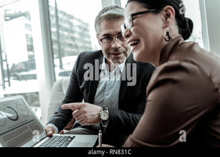 Tall grey-haired handsome man in a dark jacket and his partner having good time Stock Photo