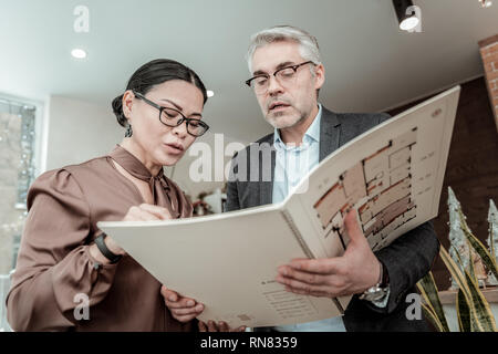 Businesswoman in a brown satin blouse explaining project details looking concentrated Stock Photo