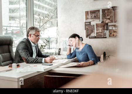 Grey-haired serious man in eyeglasses and his colleague looking serious Stock Photo