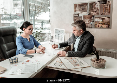 Serious grey-haired handsome man in eyeglasses signing the document Stock Photo