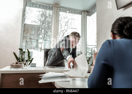 Tall grey-haired handsome man in eyeglasses looking annoyed Stock Photo