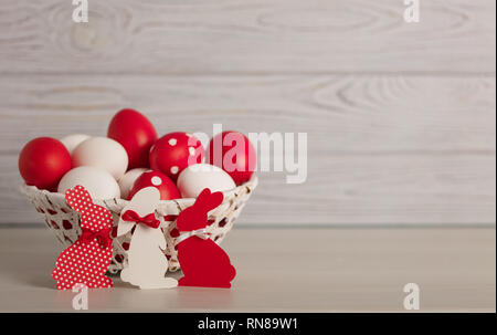 Happy Easter! Painted Easter eggs and Easter decoration - Easter bunnies with ribbons - red, white and red with white polka dots on a gray wooden back Stock Photo
