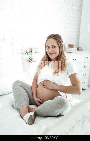 Positive long-haired pregnant woman being satisfied with her status Stock Photo