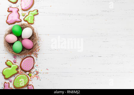 Easter greeting card with colorful gingerbread cookies and easter eggs in nest. Top view on wooden table with space for your greetings Stock Photo